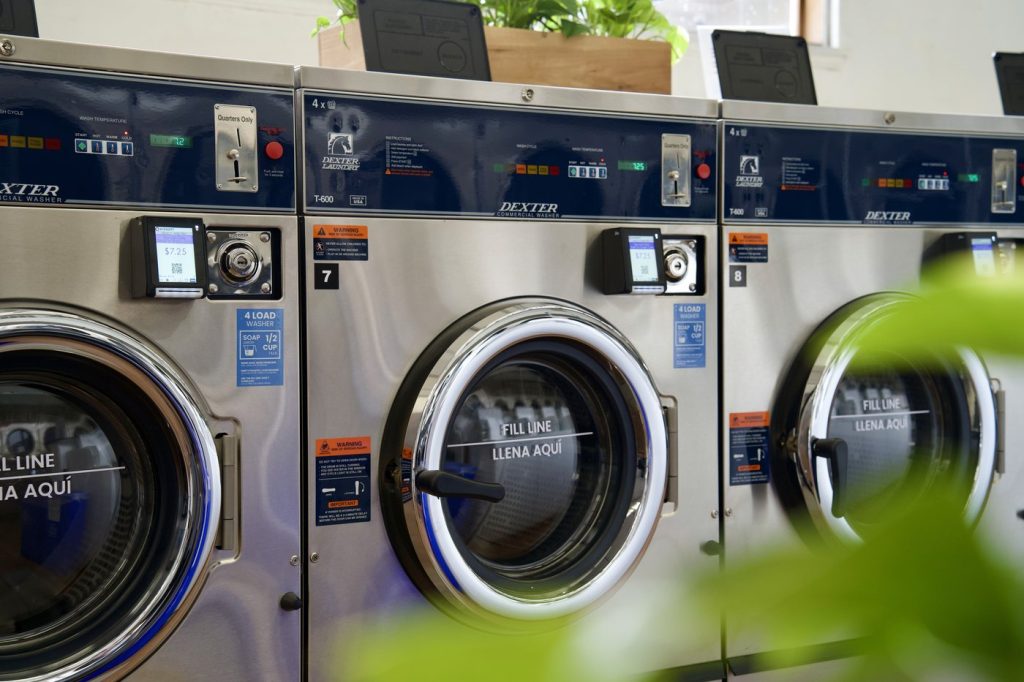 Row of Dexter commercial washers with blue lit doors and bilingual fill line labels at The Laundry Hub SF