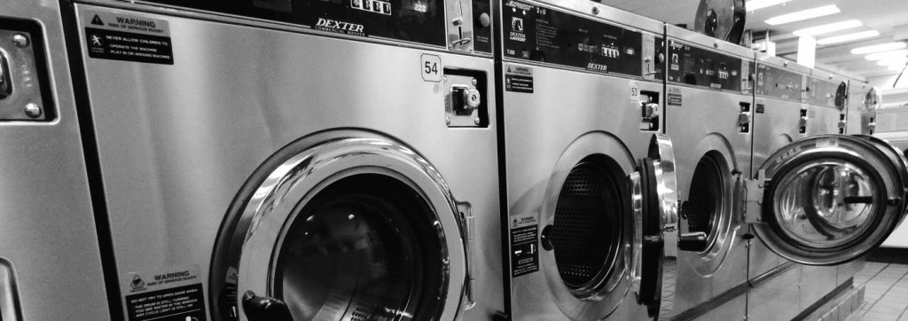 Black and white close up of a Dexter commercial washer in the machine aisle at The Laundry Hub SF