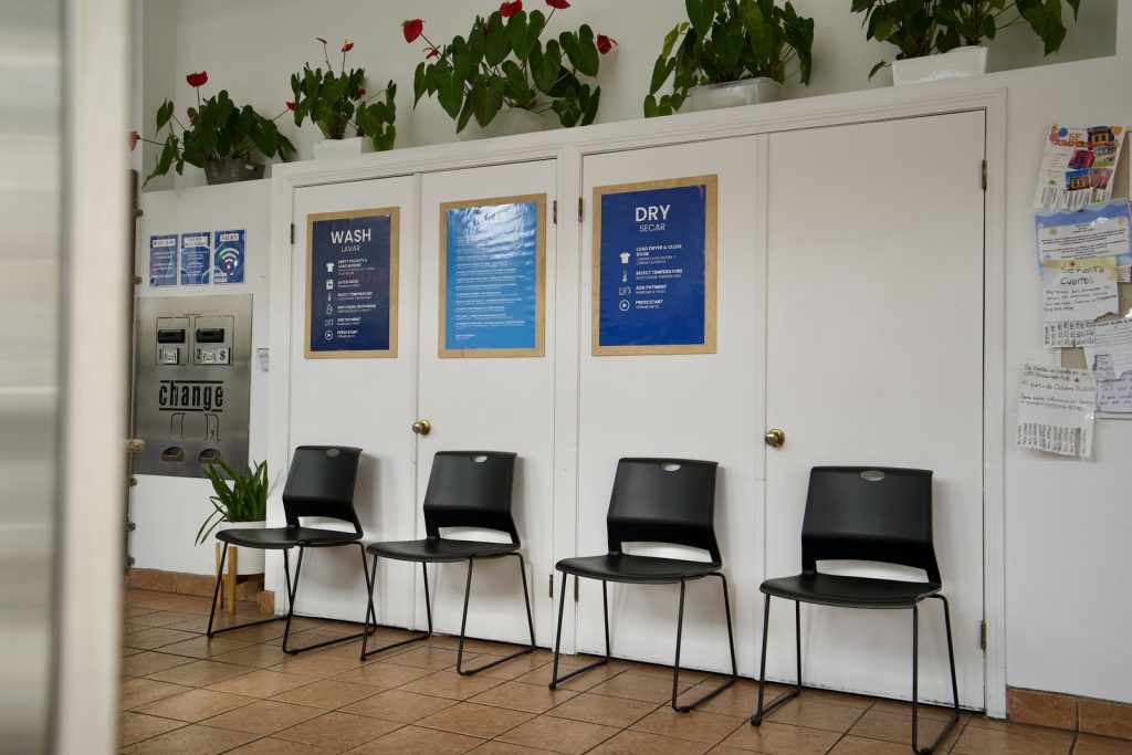 Waiting area seating below bilingual wash and dry instruction boards at The Laundry Hub SF