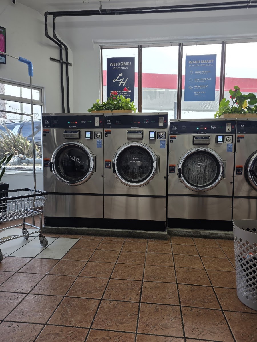 Row of commercial washers beside the storefront windows at The Laundry Hub SF