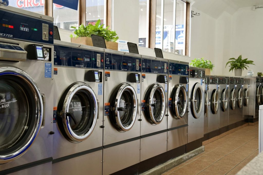 Long row of commercial washers down the tiled aisle at The Laundry Hub wash and fold laundromat in San Francisco